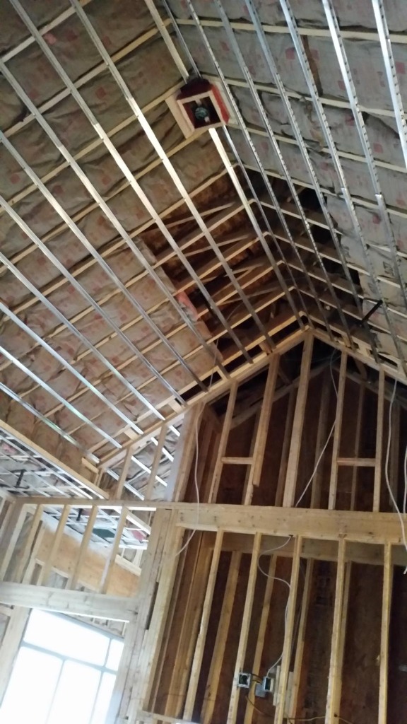 Ceiling framing with insulation being applied to roof deck